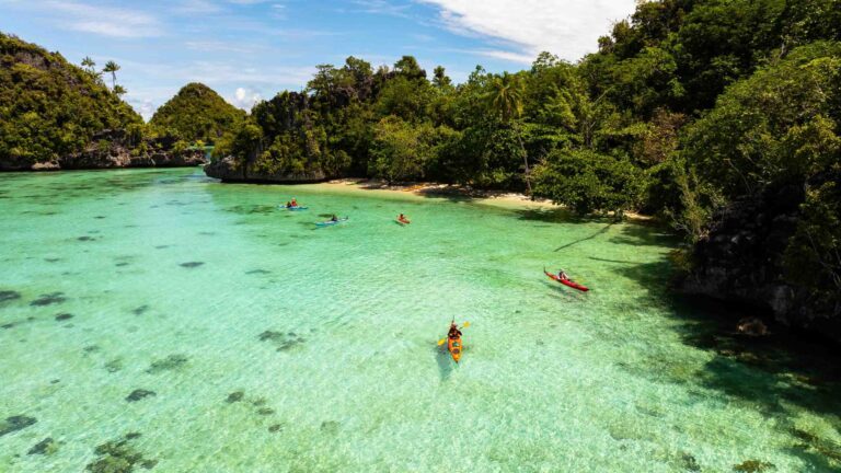 Sea Kayaking Raja Ampat Paddling on to another island Photo Josh Edwards scaled